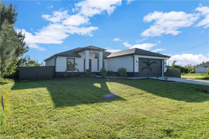 View of front facade featuring a garage and a front yard