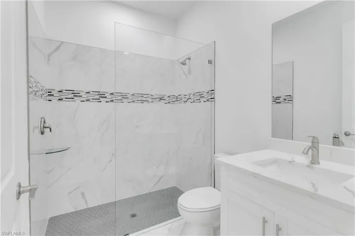 Bathroom featuring toilet, vanity, and tiled shower