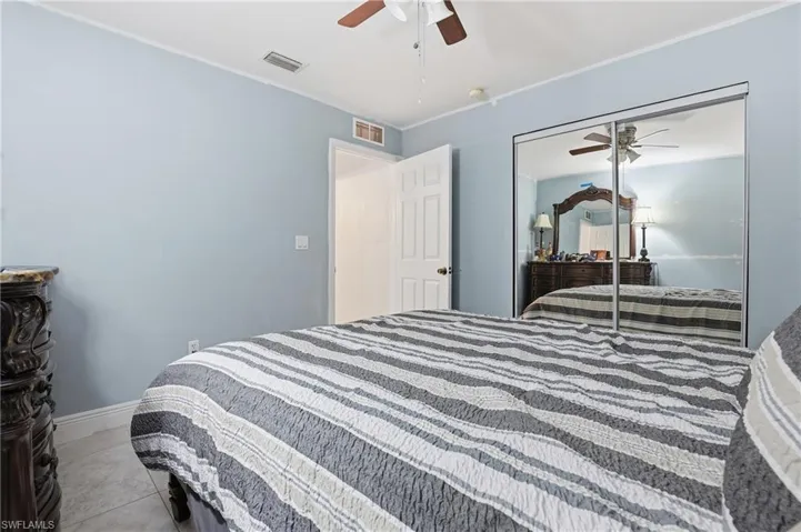 Bedroom with ceiling fan, ornamental molding, a closet, and light tile patterned floors