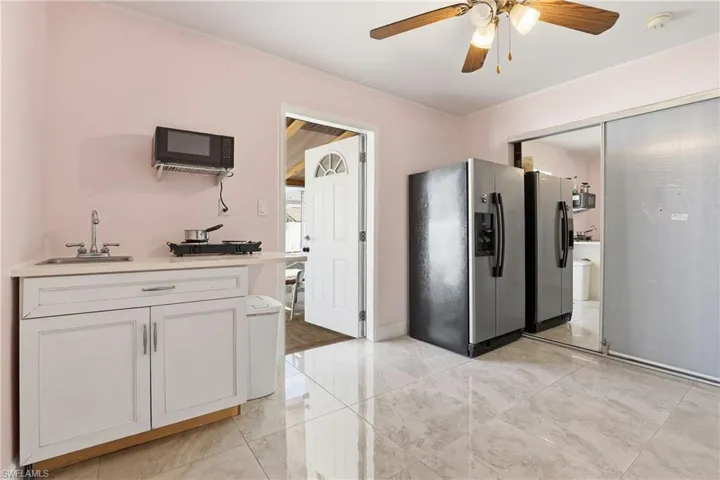 Kitchen featuring stainless steel fridge, white cabinets, ceiling fan, and black microwave