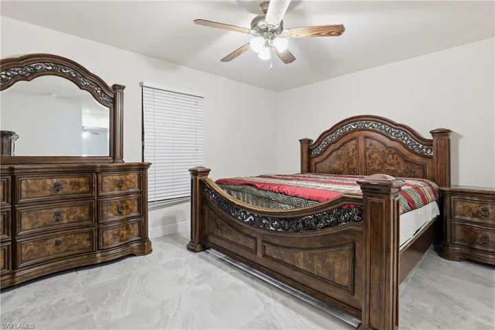 Bedroom with a ceiling fan and light marble finish flooring