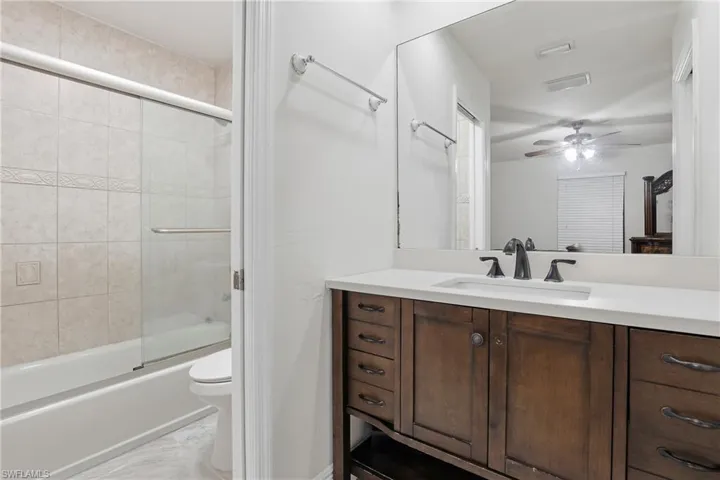 Full bathroom featuring vanity, shower / bath combination with glass door, and ceiling fan