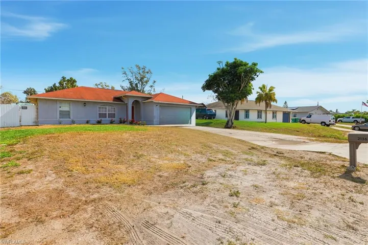 Ranch-style house featuring concrete driveway, a garage, and a gate