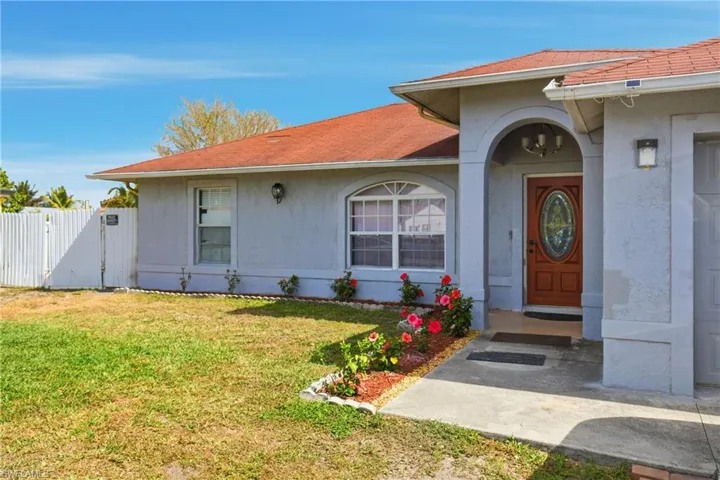 Doorway to property with a gate, a shingled roof, and stucco siding