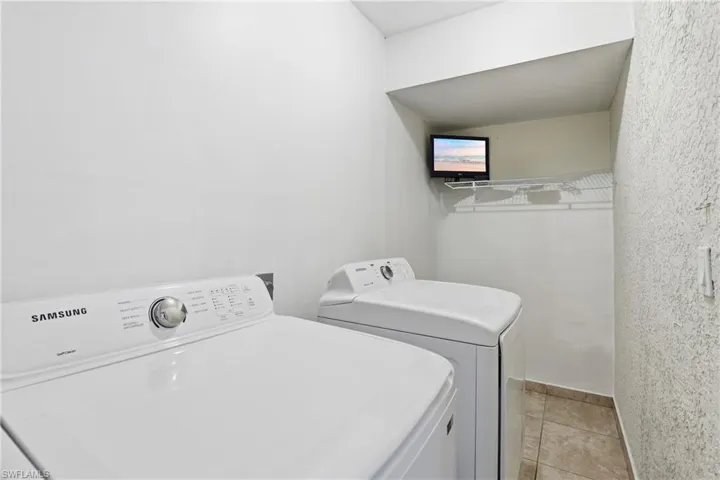 Laundry area with washing machine and dryer and light tile patterned floors