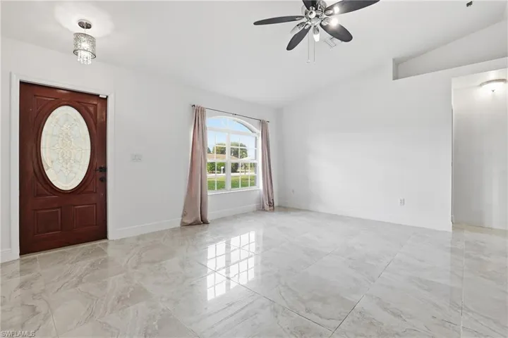 Entryway featuring vaulted ceiling, ceiling fan, and light marble finish flooring