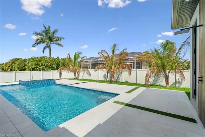 Outdoor living space featuring a rectangular swimming pool with an integrated spa, complete with blue mosaic tile accents