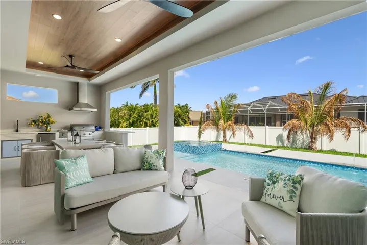 Expansive screened patio featuring an outdoor kitchen with stainless steel appliances, a built-in grill, and wood-finish ceiling accent