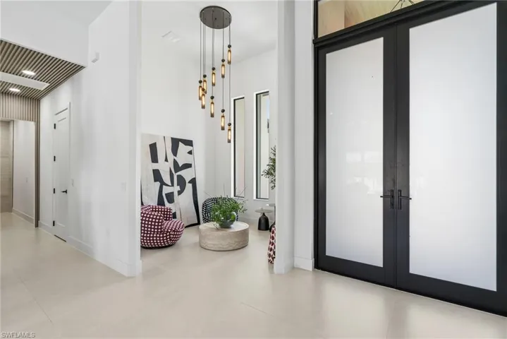 Entryway featuring black-framed double doors with frosted glass panels, high ceilings, and light-toned tile flooring