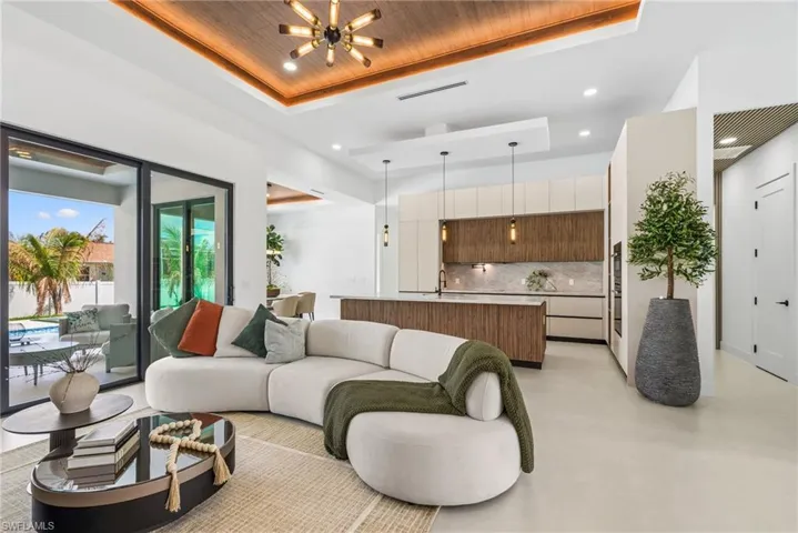 Open-concept living area with large format tile flooring and a wood-finish tray ceiling