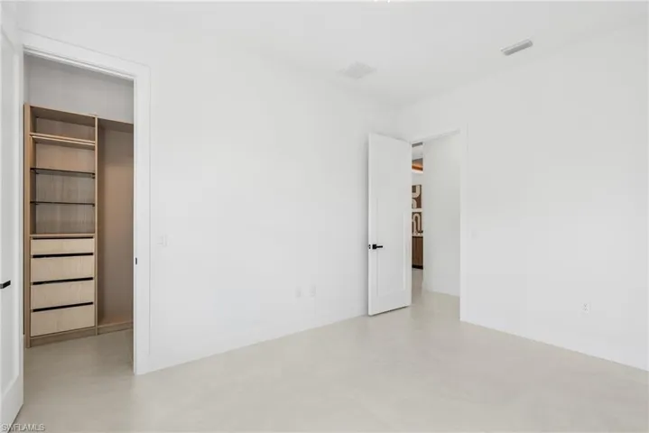 Spacious room featuring light-colored flooring and white walls