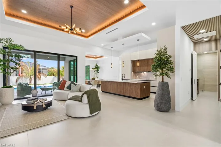 Open-concept living area featuring a wood-finish ceiling inset with recessed lighting and a modern chandelier