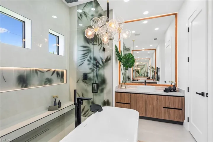 Contemporary bathroom featuring a freestanding tub, glass-enclosed shower with botanical design, and a floating wood-finish vanity with a vessel sink