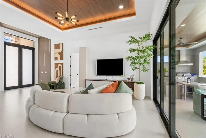 Living area featuring a recessed wood-finish ceiling with integrated lighting and a contemporary chandelier