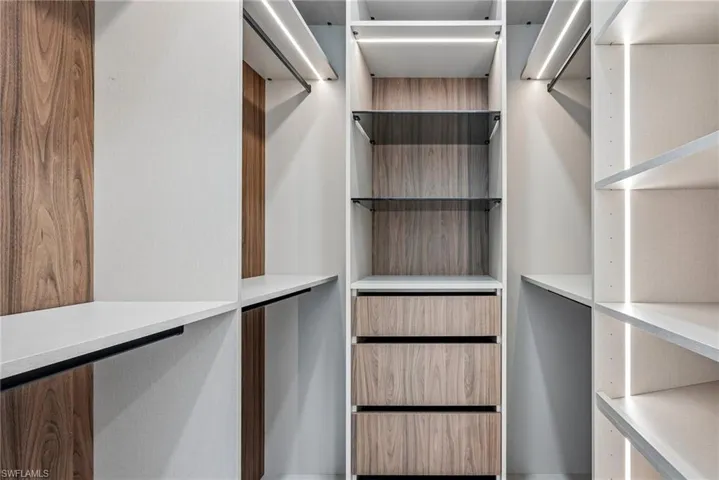 Custom closet system featuring white shelving and wood-finish paneling
