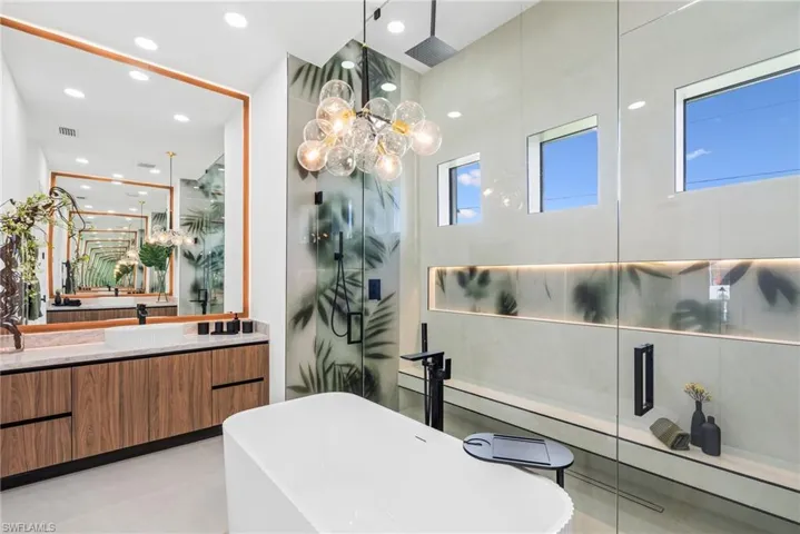 Contemporary bathroom featuring a freestanding tub, glass-enclosed shower with custom botanical-patterned glass, and a wood-finish vanity with a rectangular basin