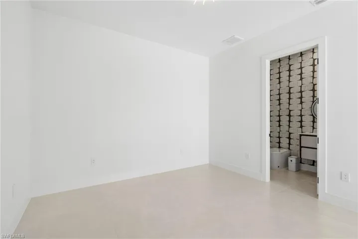 Neutral-toned tile flooring extends throughout this room, complemented by crisp white walls and baseboards