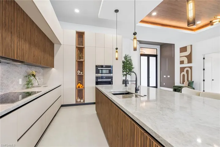 Gourmet kitchen featuring a large stone-top island with an undermount sink and black faucet