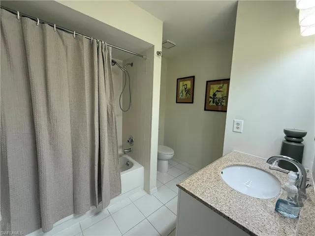 Full bath featuring light tile patterned flooring, vanity, and shower / tub combo with curtain