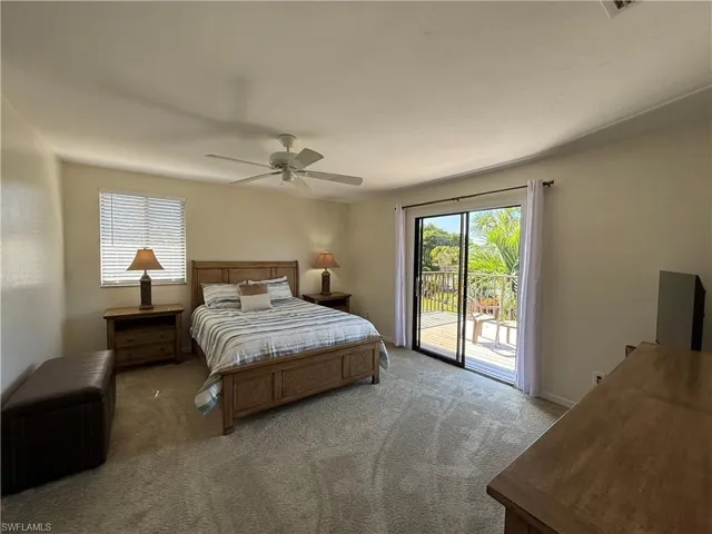 Carpeted bedroom with access to exterior, multiple windows, and a ceiling fan