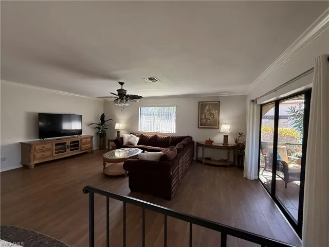 Living area featuring crown molding, dark wood finished floors, and ceiling fan