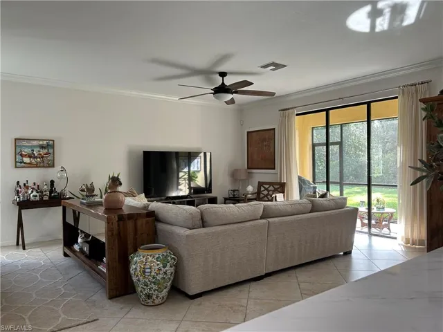 Living area with crown molding, a ceiling fan, and light tile patterned floors