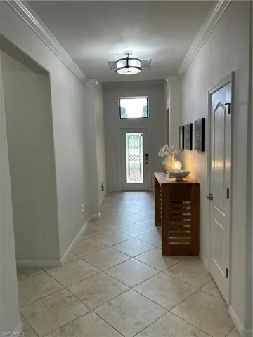Entryway featuring ornamental molding and light tile patterned floors