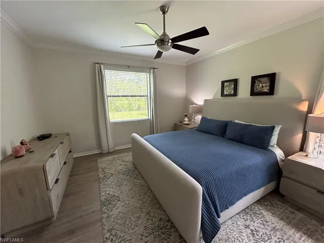 Bedroom featuring wood finished floors, ornamental molding, and ceiling fan