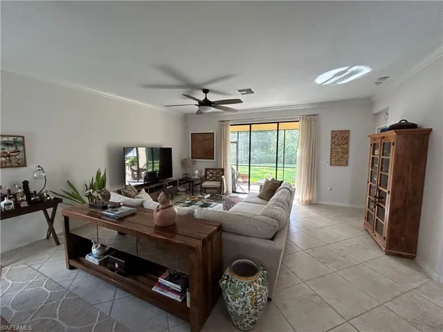 Living room with crown molding, light tile patterned floors, and ceiling fan