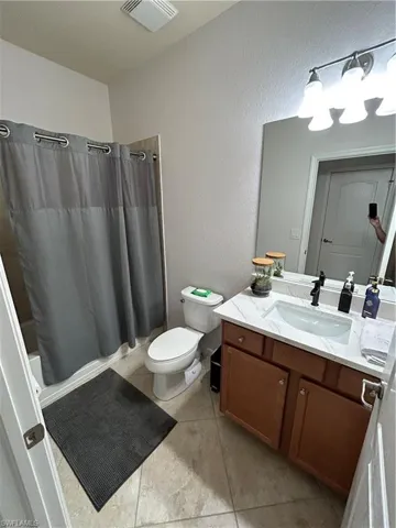 Full bath with a textured wall, vanity, light tile patterned floors, and shower / tub combo with curtain
