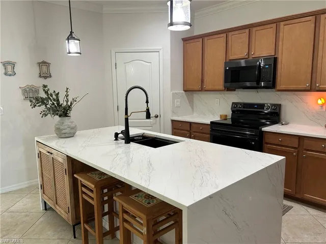 Kitchen featuring light tile patterned floors, brown cabinetry, electric range, ornamental molding, and tasteful backsplash