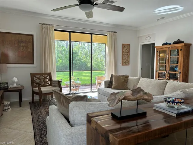 Tiled living area featuring crown molding and ceiling fan