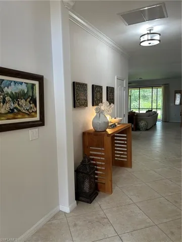 Hallway featuring ornamental molding and light tile patterned flooring