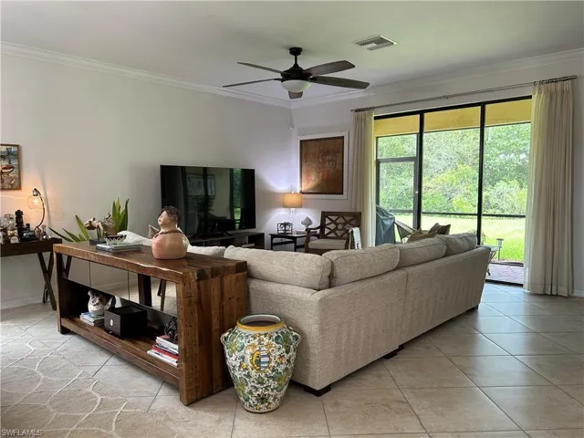 Living area featuring crown molding, light tile patterned floors, and ceiling fan