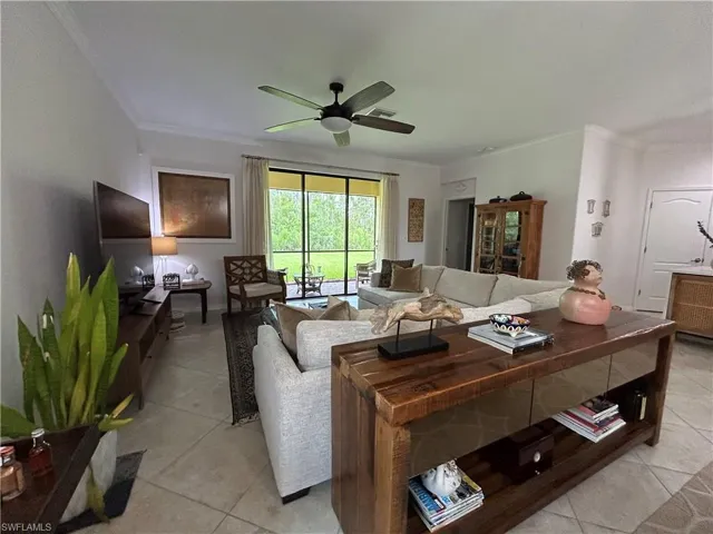 Living area featuring ornamental molding, light tile patterned flooring, and a ceiling fan