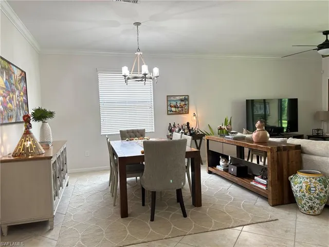 Dining area with ornamental molding, light tile patterned floors, and a chandelier