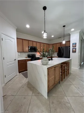 Kitchen featuring brown cabinets, a kitchen island, range, a kitchen breakfast bar, and fridge