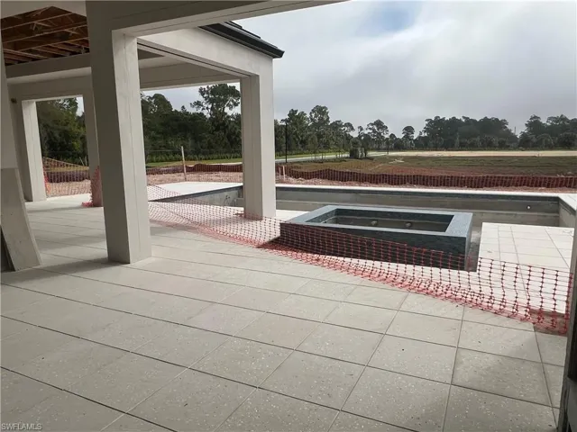 View of patio featuring a pool with connected hot tub and view of wooded area