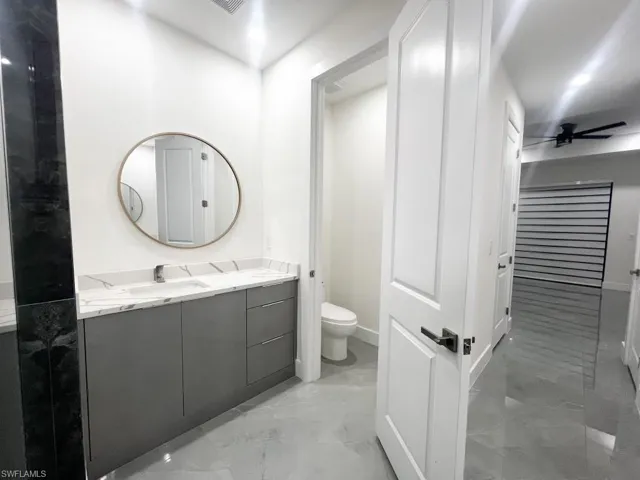 Bathroom with vanity, a ceiling fan, and light marble finish flooring