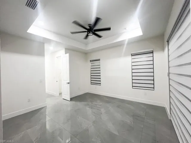 Unfurnished bedroom with a ceiling fan and a tray ceiling