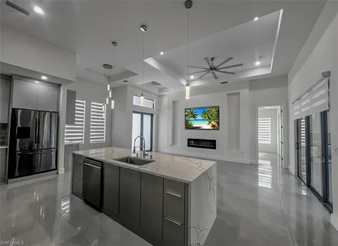 Kitchen with modern cabinets, a center island with sink, a glass covered fireplace, stainless steel appliances, and open floor plan
