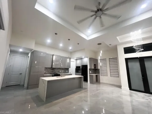 Kitchen featuring gray cabinetry, modern cabinets, backsplash, light stone countertops, and a ceiling fan