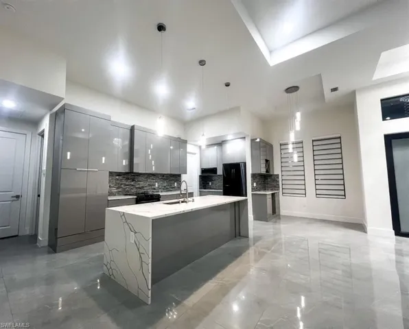 Kitchen featuring gray cabinetry, modern cabinets, light stone counters, and tasteful backsplash