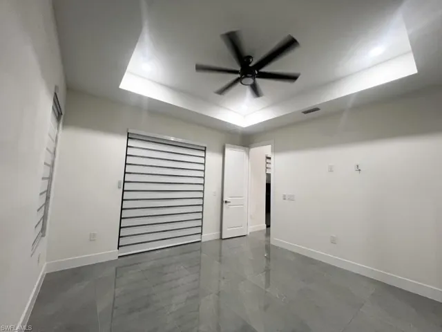 Spare room featuring a raised ceiling and ceiling fan