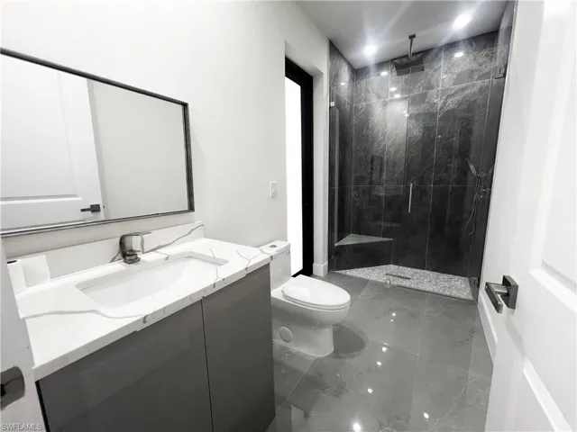 Full bathroom with vanity, a marble finish shower, and light marble finish flooring