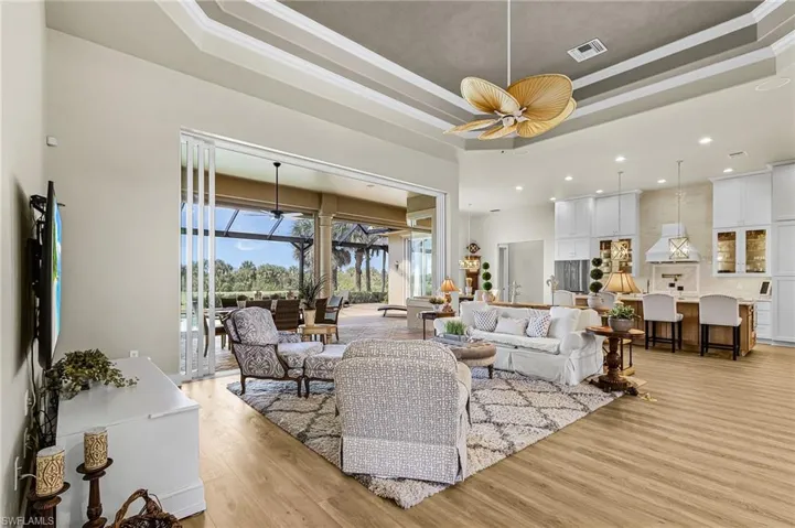 Living room featuring a sunroom, a tray ceiling, light wood-style floors, ceiling fan, and recessed lighting