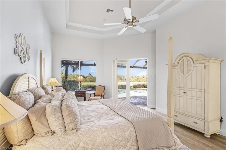 Primary Bedroom featuring access to outside, ceiling fan, light wood-style floors, and a raised ceiling