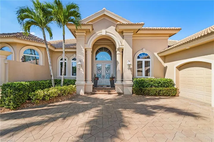 Property entrance featuring french doors, decorative driveway, an attached garage, a tiled roof, and stucco siding