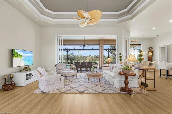 Living room with a sunroom, ceiling fan, healthy amount of natural light, light wood-type flooring, and ornamental molding