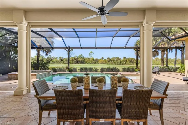 View of patio with a sunroom, a lanai, a ceiling fan, a pool with connected hot tub, and outdoor dining space